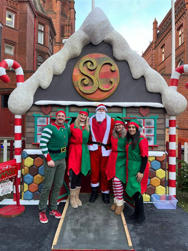 Amtico staff standing outside Santa's grotto in Christmas outfits.