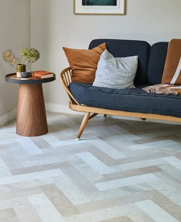 Living space features Amtico DC637 Parquet Large with a wood side table and blue sofa.
