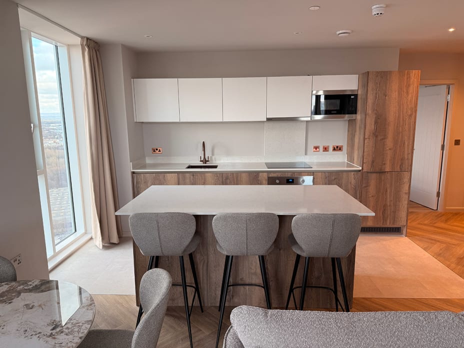The kitchen space features Pampas laid in Uniform Tile, paired with Mulled Oak in a Herringbone Plank and Polished Copper stripping.