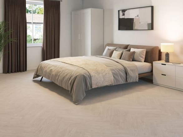 Light-coloured wood-effect floor tiles in parquet laying pattern in a cream coloured bedroom