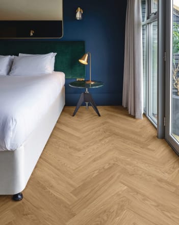 Sandy-coloured wood-effect floor planks in a parquet laying pattern in a bedroom