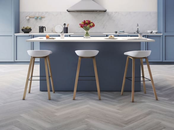 Cool silver-toned woodeffect floor planks in parquet laying pattern in a blue-coloured kitchen
