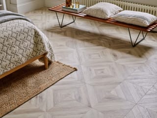 Light oak-effect small floor planks in parquet laying pattern in a bedroom