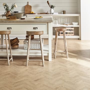 Light wood-effect flooring tiles in a parquet laying pattern in a kitchen