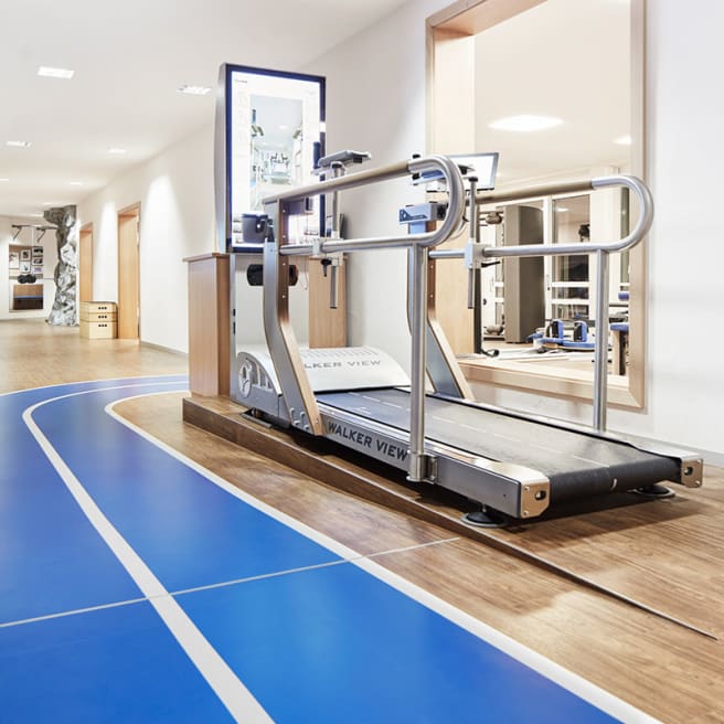 A bright blue and white path winds through a gym, with light wood-effect floor planks