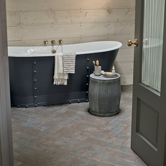 Modern metal flooring tiles with polished copper borders in a bathroom