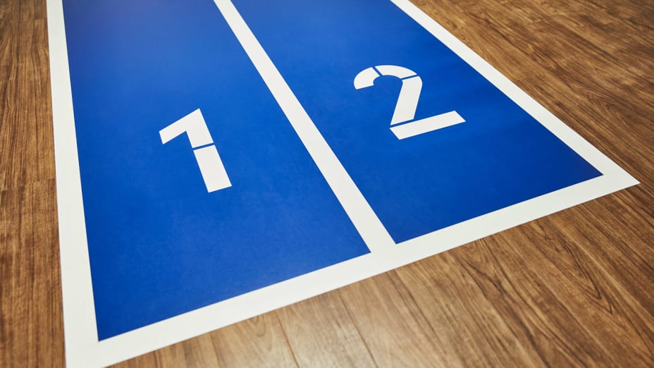 A bright blue and white path with the numbers 1 and 2, with light wood-effect floor planks either side